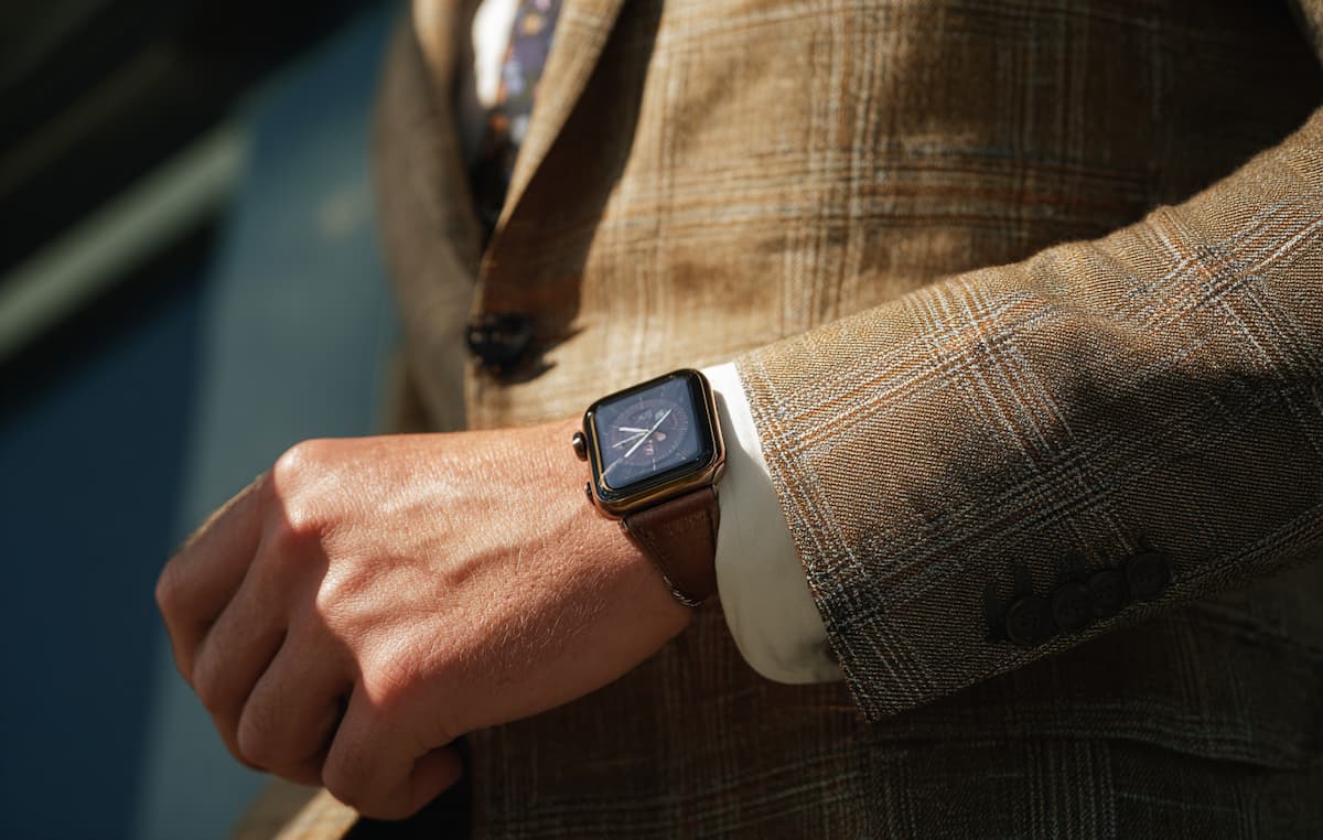 スーツを着た男性が手首のアップルウォッチを不安そうな表情で見つめる主観的な視点の写真